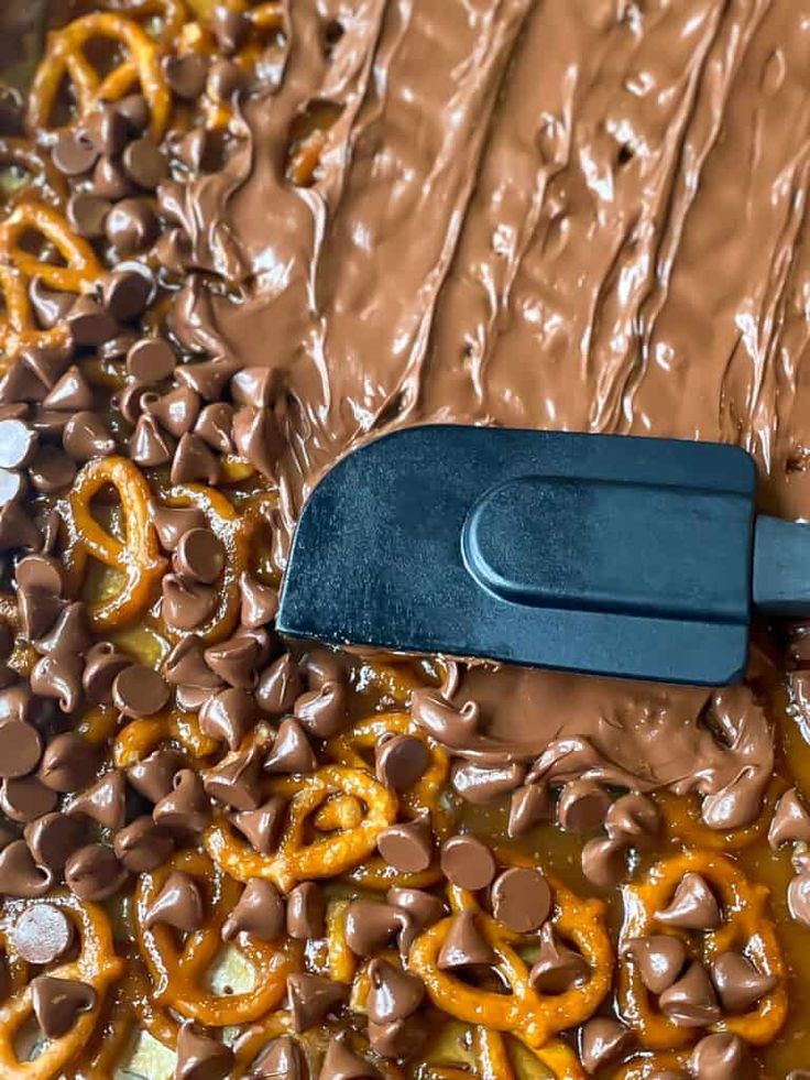 chocolate and pretzels are being spread on top of each other with a spatula