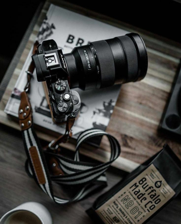 a camera sitting on top of a wooden table next to a cup of coffee and other items