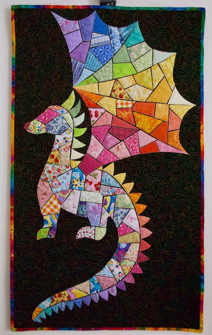 a colorful dragon made out of many different types of paper and threads on a black background