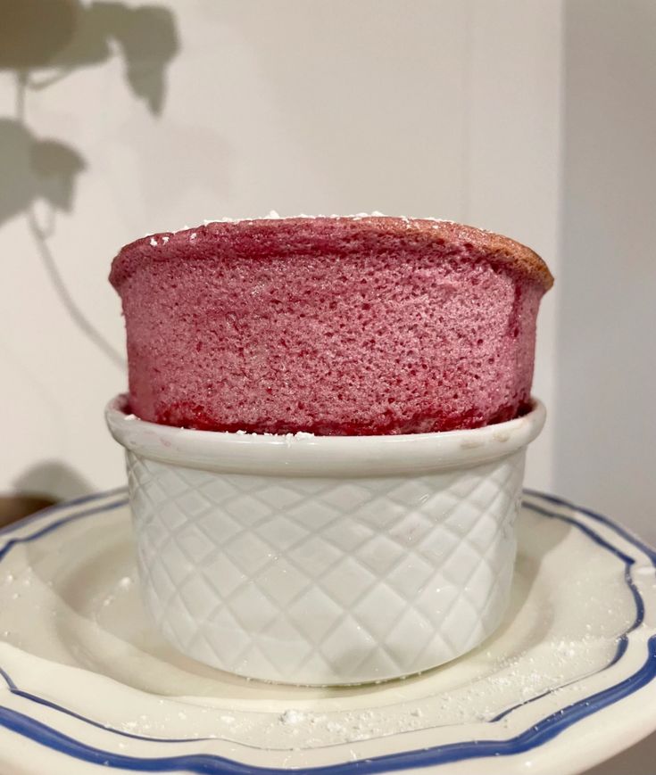 a red cake in a white bowl on a plate