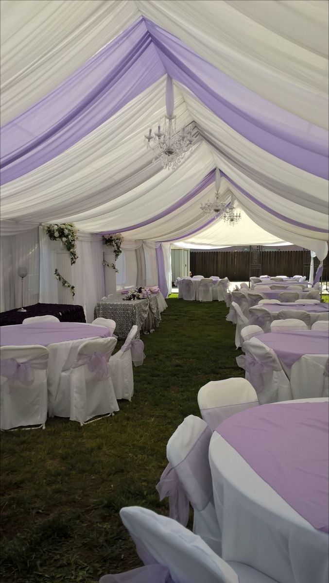 the inside of a tent with white and purple linens