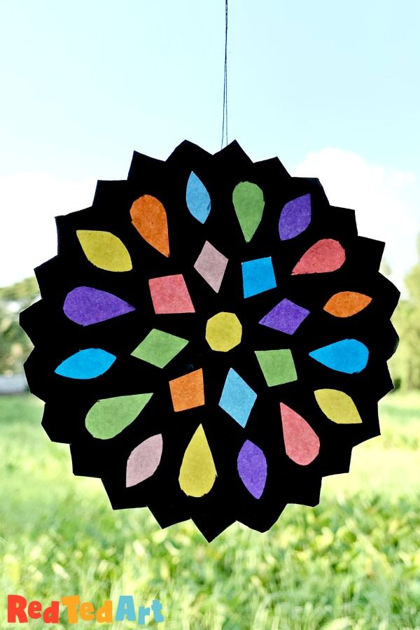 a paper plate hanging from a string in front of a field with green grass and blue sky