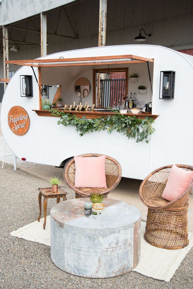 two wicker chairs sitting in front of a food truck with plants growing on it