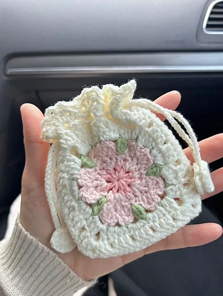 a hand holding a small crocheted bag in it's left hand,