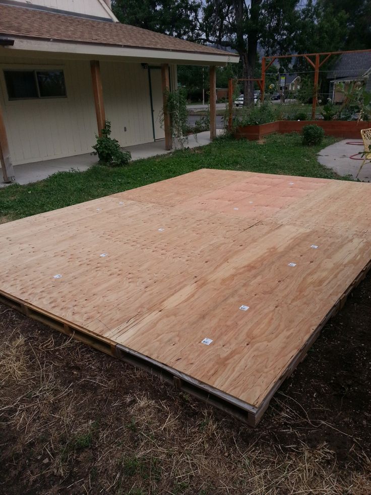 a large wooden floor laying on top of dry grass in front of a house and yard