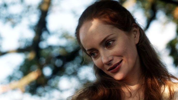 a woman with red hair is smiling for the camera