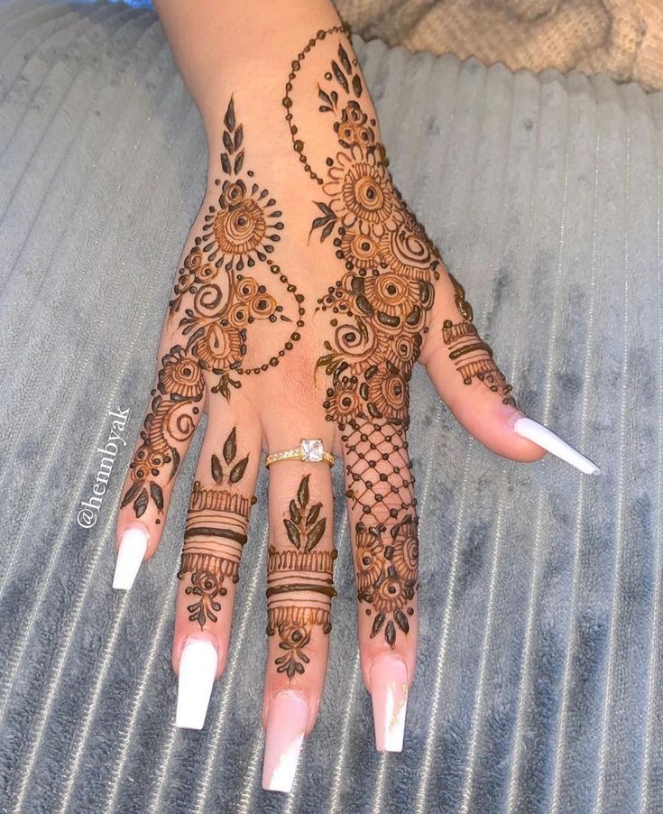 a woman's hand with henna tattoos on it and white nails in front of her