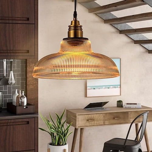 a wooden table sitting under a light fixture in a kitchen next to a potted plant