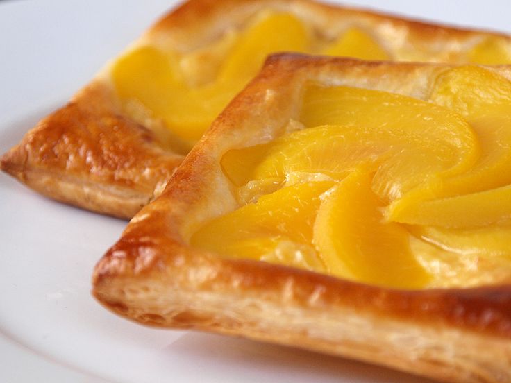 two pieces of bread with yellow fruit on them sitting on top of a white plate