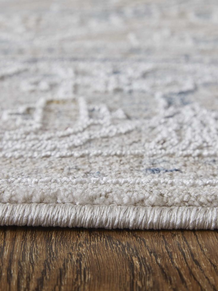 a close up view of an area rug on a wooden floor with white and gray colors