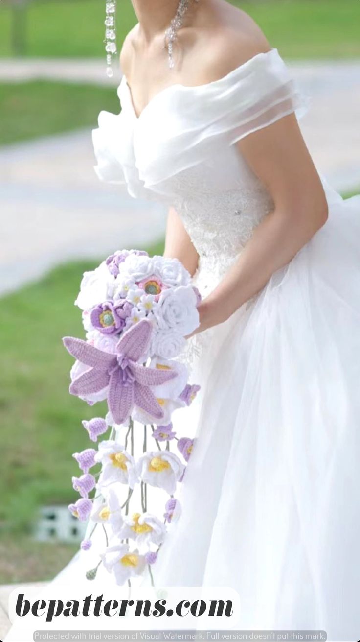 a woman in a white wedding dress holding a purple and white bouquet with flowers on it