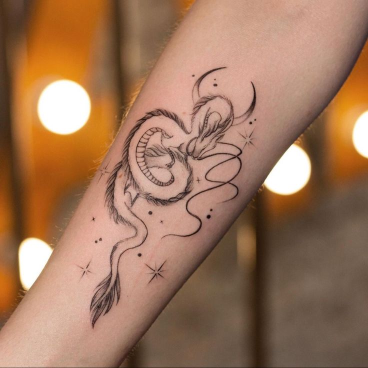 a woman's arm with a dragon tattoo on the left side of her arm