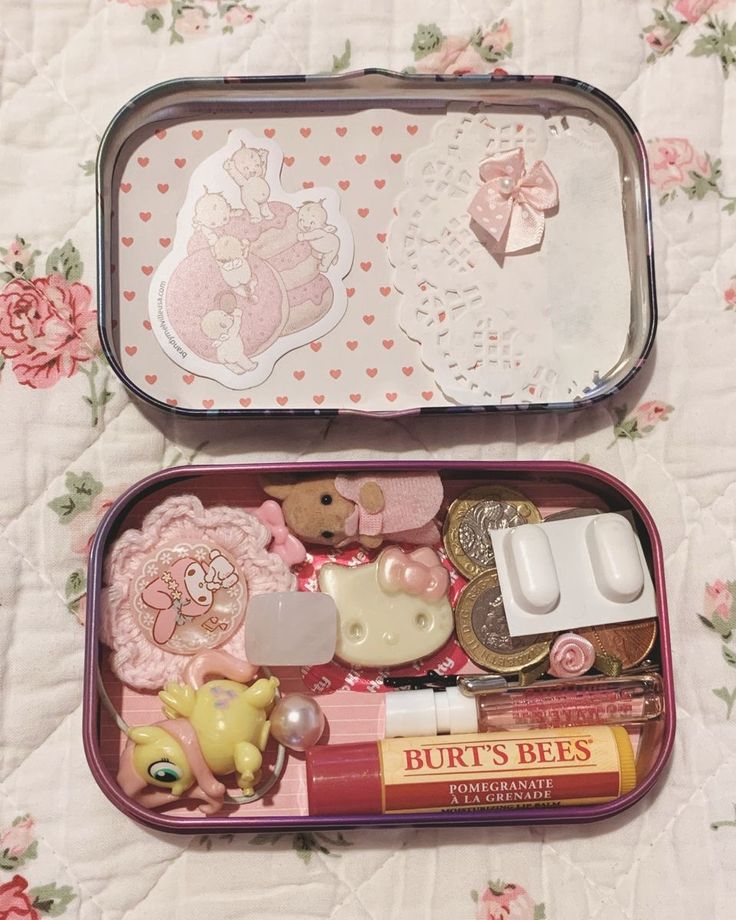 two tins filled with different types of items on a tablecloth covered surface and pink flowers