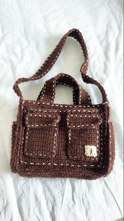 a crocheted brown purse sitting on top of a white sheet