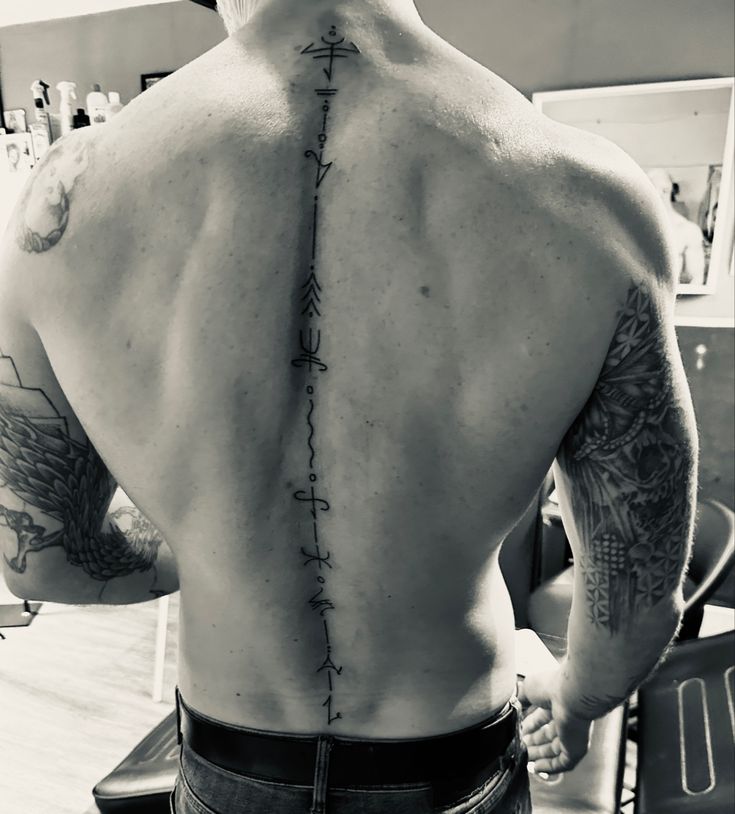 the back of a man with tattoos on his upper and lower part of his body