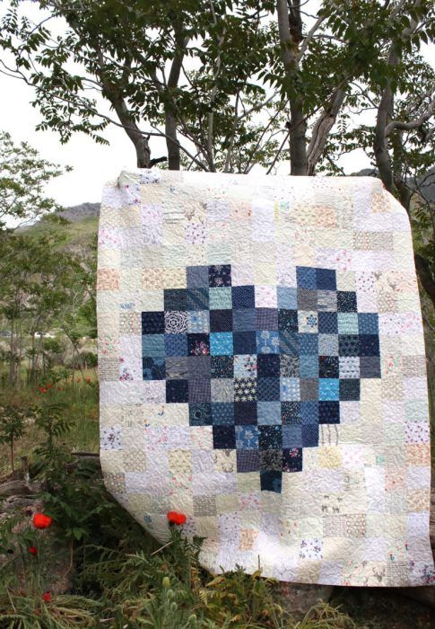 a blue and white quilt hanging from a tree