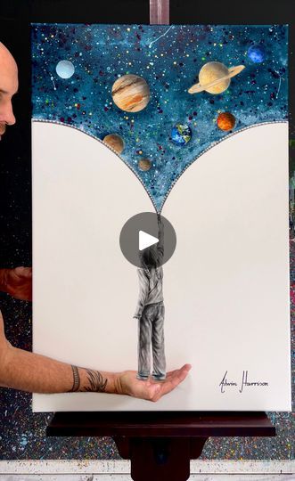 a man holding up an art piece with planets in the background