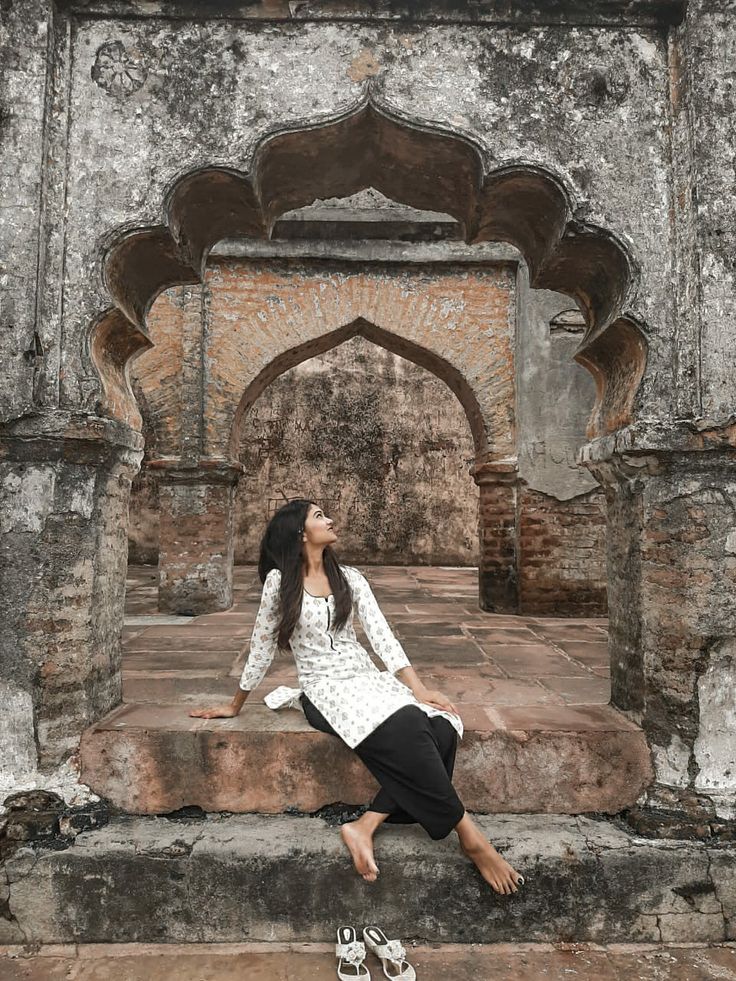 a woman sitting on top of a stone bench