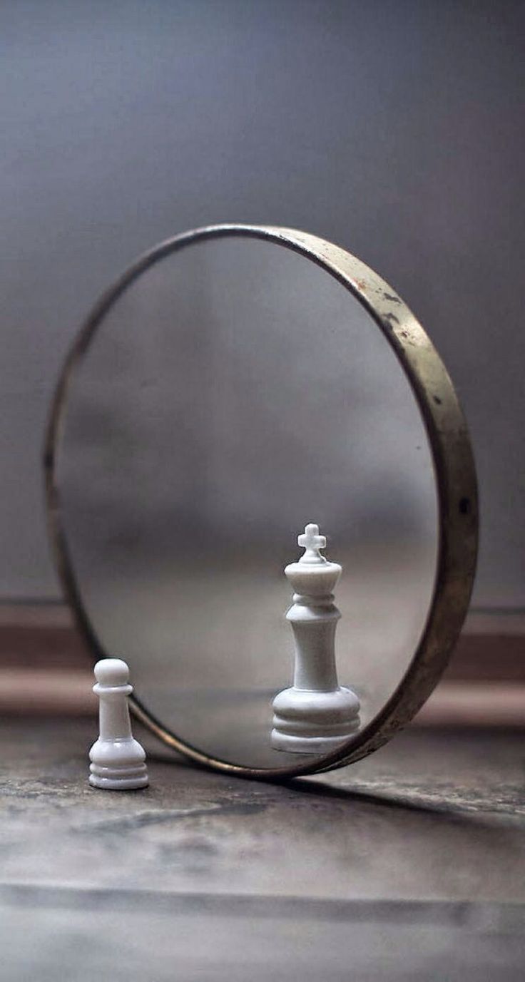 a mirror with a chess piece in front of it and a white pawn standing next to it