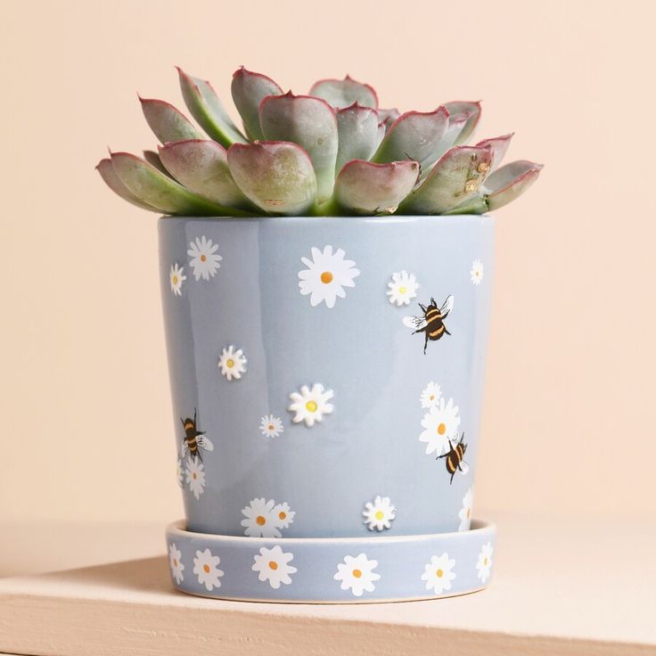 a potted plant with flowers and bees on it sitting on a shelf next to a wall