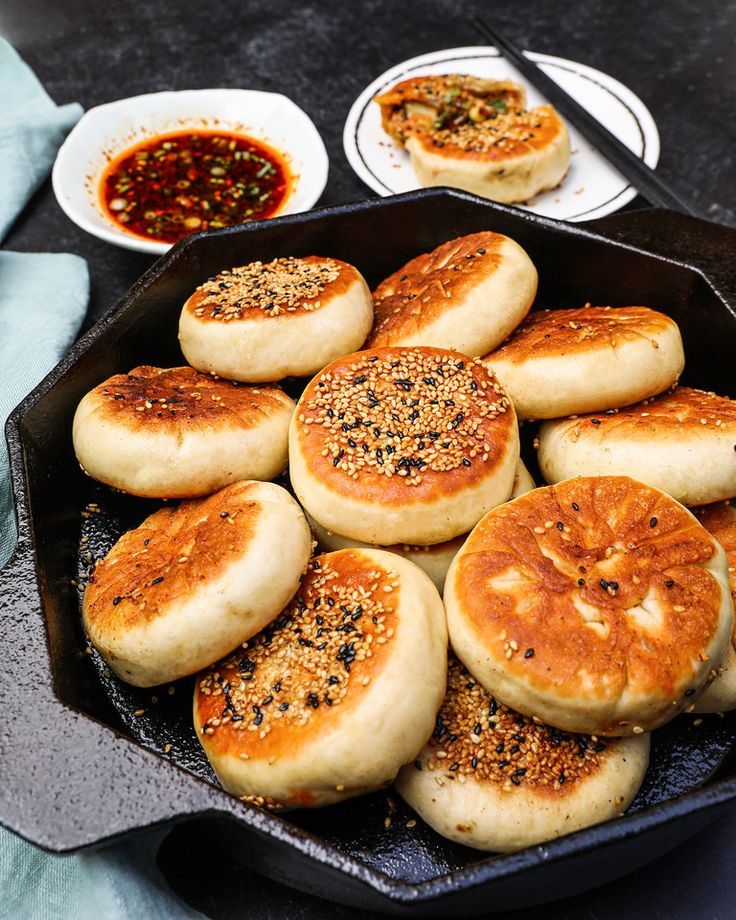 a pan filled with baked goods on top of a table next to bowls of sauce