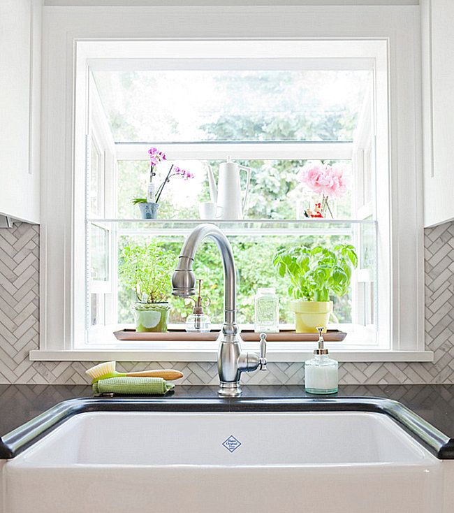 a white kitchen sink under a window with potted plants in the window sill