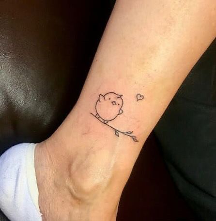 a small tattoo on the ankle of a person with a bird sitting on a branch