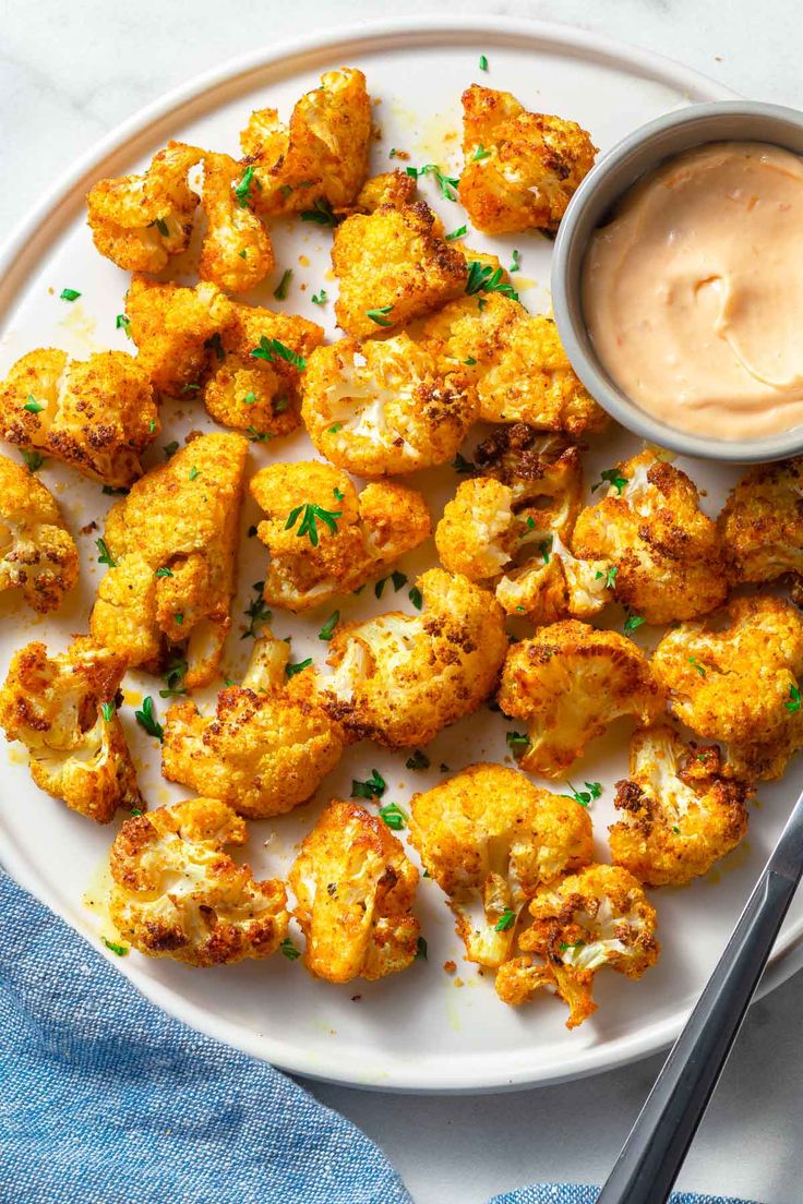 a white plate topped with fried cauliflower and dipping sauce