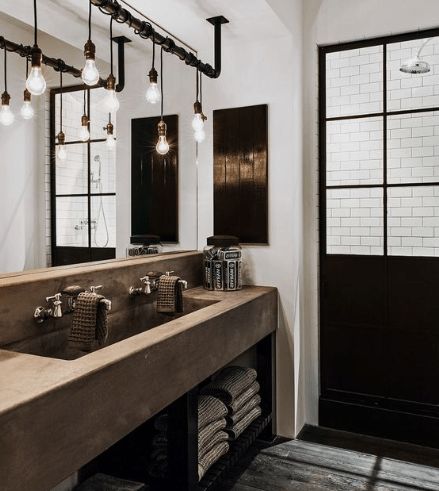 a bathroom with double sinks, mirrors and lights hanging from the ceiling over it's mirror