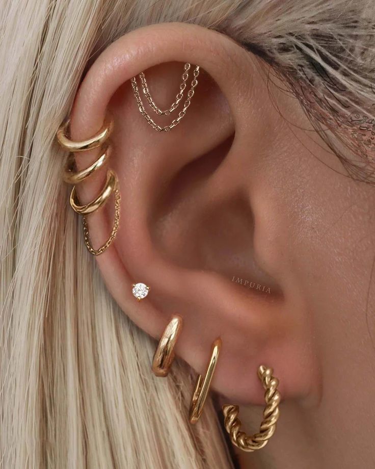 a woman with blonde hair wearing three different ear piercings and one is in the shape of a spiral