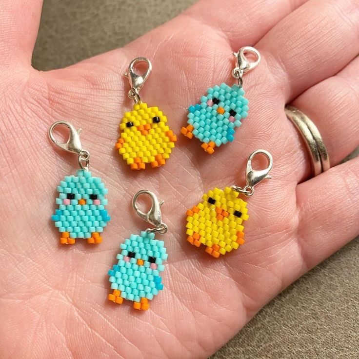 four pieces of bead art in the palm of a person's hand,