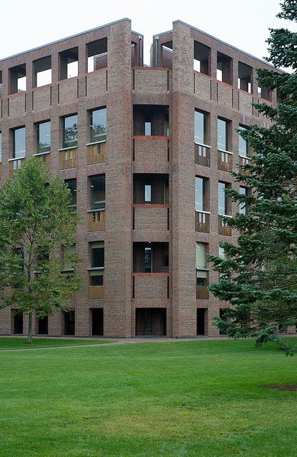 a large brick building sitting on top of a lush green field next to tall trees