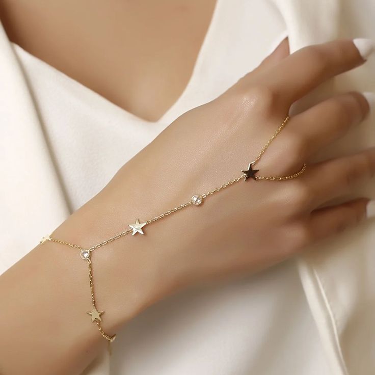 Revel in bohemian charm with our slave bracelet! Featuring shimmering zircon crystals and playful star accents, this unique accessory will have you shining like a star in no time. (Quirky and fun, without taking ourselves too seriously!) Metal: 925 sterling silver Finish: 18k gold Gemstone: white zirconia Bracelet length: adjustable with 4 cm extender (1.5") Chain: cable link Clasp: spring ring Hypoallergenic & nickel-free Don’t forget, proper care of your gold-plated jewelry will preserve its appearance for a long time. Keep it shining bright by using the soft side of the provided JFW polishing cloth Gold Party Jewelry With Star Charm, Adjustable Delicate Jewelry With Star Charm, Dainty Star Charm Jewelry For Party, Dainty Jewelry With Star Charm For Party, Elegant Adjustable Chain Bracelet With Star Charm, Rose Gold Star Jewelry For Parties, Star-shaped Cubic Zirconia Jewelry For Party, Elegant Star-shaped Chain Bracelet For Gift, Dainty Silver Star-shaped Chain Bracelet