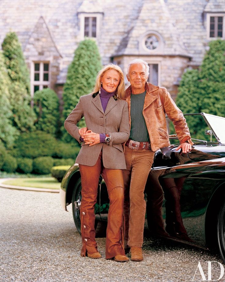 two people standing next to a car in front of a house