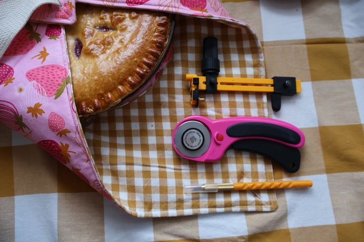 some tools are laying out on a checkered tablecloth with a pie in the bag