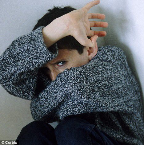 a man with his hand on the top of his head while leaning against a wall