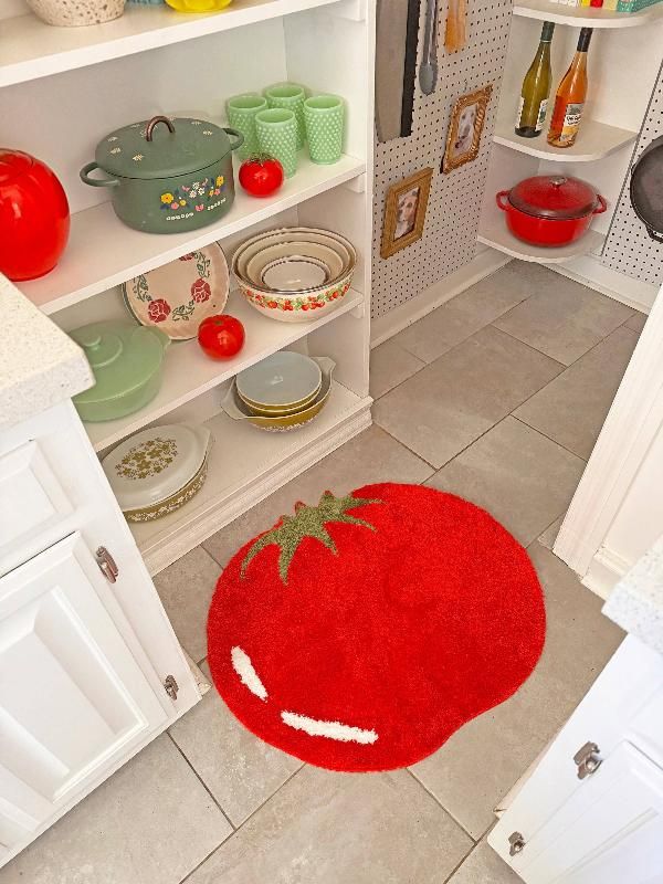 a red rug is on the floor in front of a white book shelf with dishes and utensils