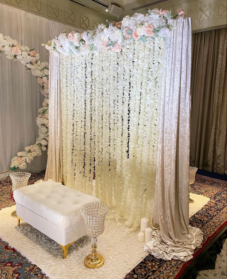 a white couch sitting in front of a flower covered stage with flowers on the wall