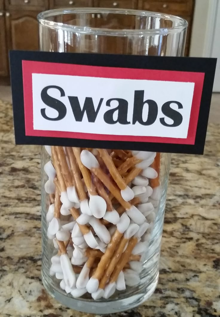 a glass filled with marshmallows sitting on top of a counter next to a sign that says swabs