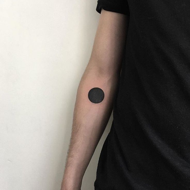 a man with a black dot tattoo on his arm