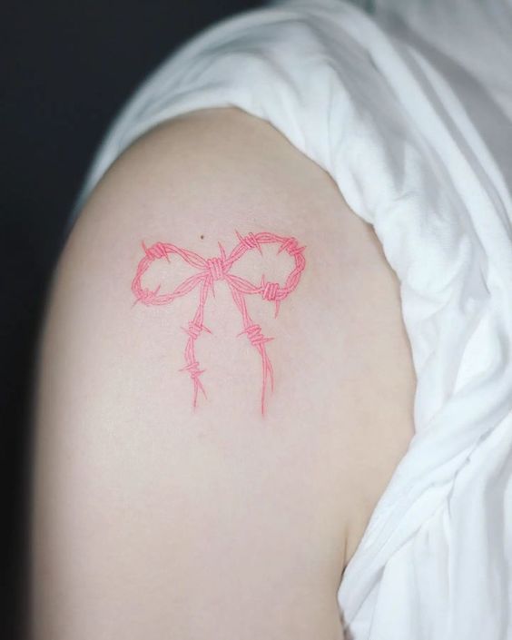 a woman's shoulder with a bow tattoo on her left arm and the word love written in red ink