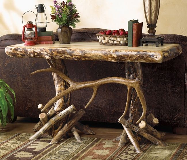 a wooden table with antlers on it in front of a brown couch and lamp