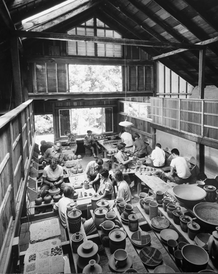 an old black and white photo of people working in a pottery shop with bowls on the tables