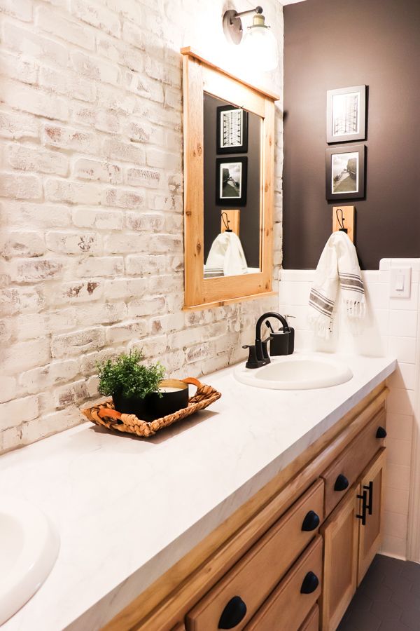 a bathroom with two sinks and a brick wall