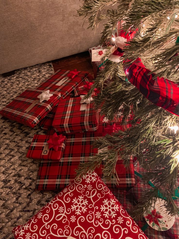 presents under the christmas tree are wrapped in red and green plaid paper with snowflakes on them