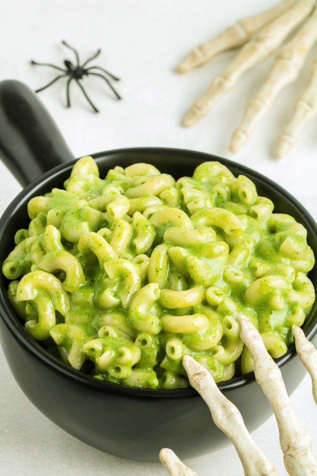 a black bowl filled with green macaroni and cheese