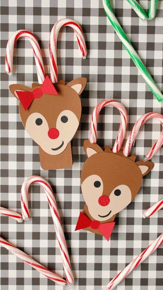 some candy canes and paper reindeer decorations on a checkered tablecloth with green straws