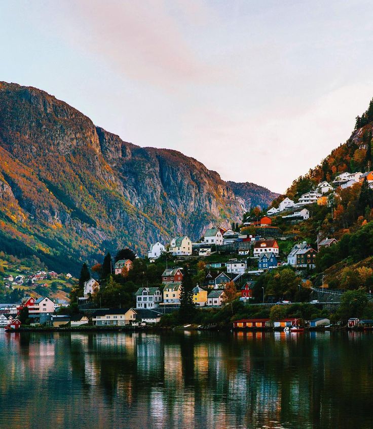 a lake with houses on it and mountains in the background