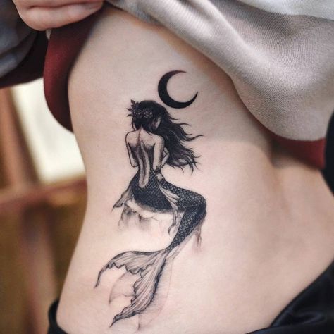 a woman with a tattoo on her stomach is standing in front of the moon and fish