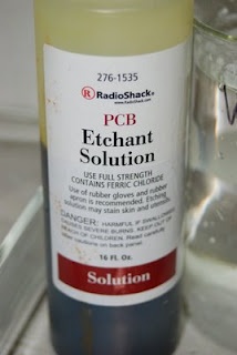 a bottle of pcb enhant solution next to a glass of water